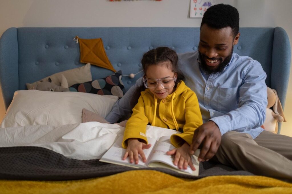 a dad and child reading in bed