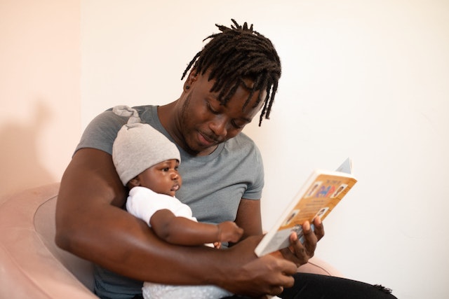 Dad reading a book to his baby bo