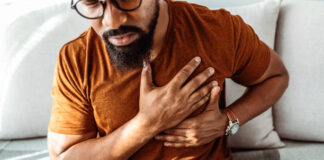 Shot of an African American man holding his chest in pain indoors