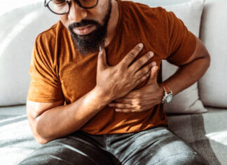 Shot of an African American man holding his chest in pain indoors