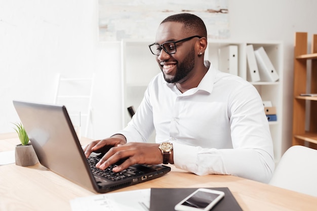 portrait smiling african american businessman white shirt eyewear sitting working his laptop office isolated 574295 456