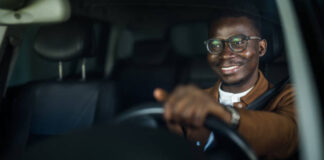 Cheerful young African American man enjoys driving his car.