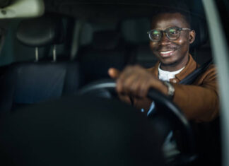 Cheerful young African American man enjoys driving his car.