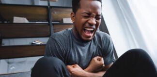 stock photo stressed african american man screaming while having panic attack home