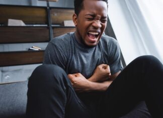 stock photo stressed african american man screaming while having panic attack home