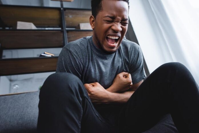 stock photo stressed african american man screaming while having panic attack home