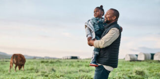 Shot of a mature man carrying his adorable daughter on a cow farm