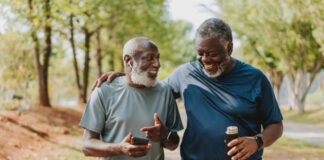 Two black senior friends walking together in public park