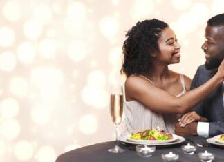 i love you attractive black woman touching her handsome man cuddling in restaurant having festive dinner together photo